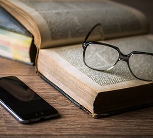 Un livre ouvert sur lequel sont déposées des lunettes - Un cellulaire