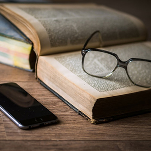 Un livre ouvert sur lequel sont déposées des lunettes - Un cellulaire