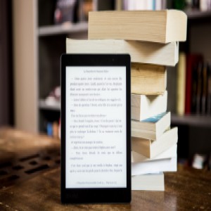 Livres empilés et liseuse électronique appuyée sur cette pile.