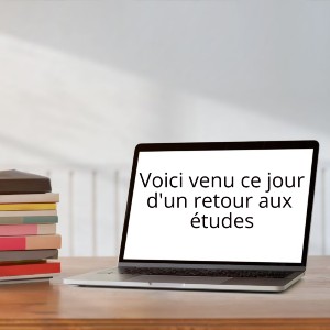 Portable ouvert et livres sur un bureau. Inscription sur l'écran: Voici venu ce jour d'un retour aux études.